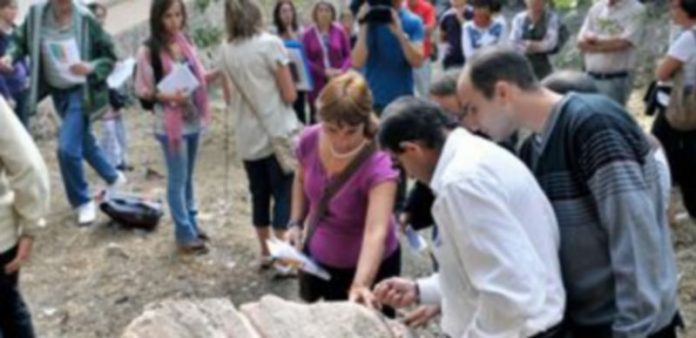 Varios participantes tocando una de las rocas del período Cretácico que se encuentra en la calle Gascos. / Kamarero.