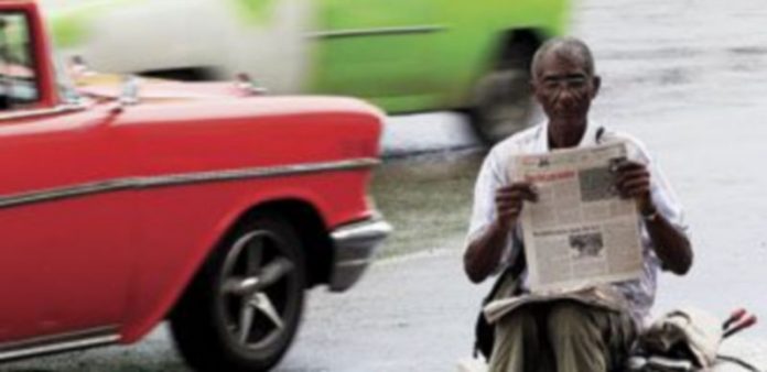 Los cubanos ya no necesitarán un permiso especial para salir de la isla Un hombre lee en ‘Granma’ el texto que proclama la nueva normativa. / Reuters